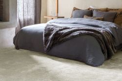 Cosy neutral bedroom with thick carpet and faux fur blanket on the bed